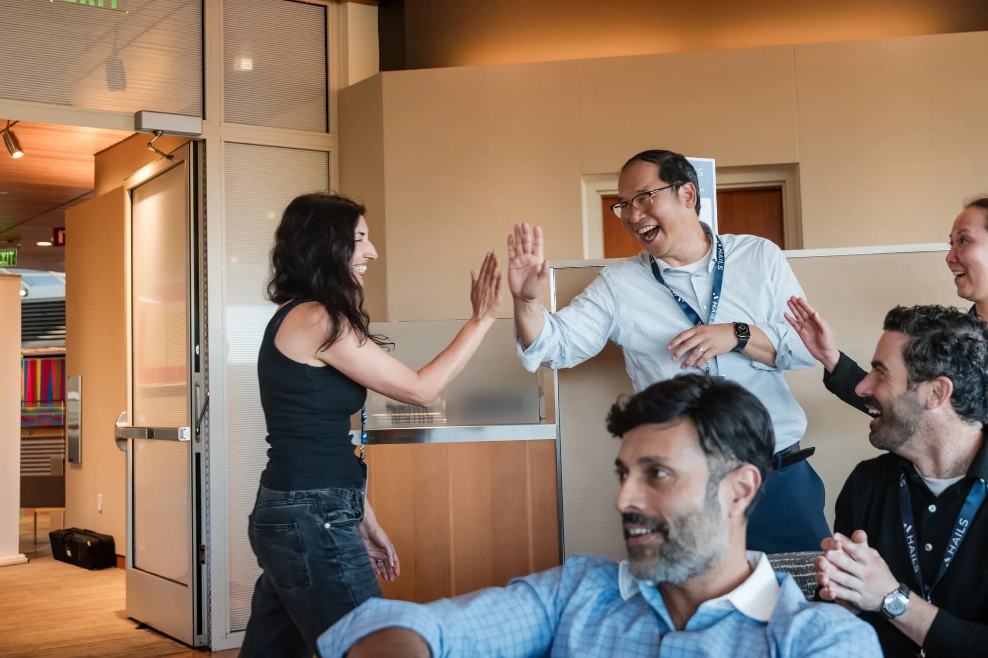 Two attendees exchanging a high five in the hallway as others laugh